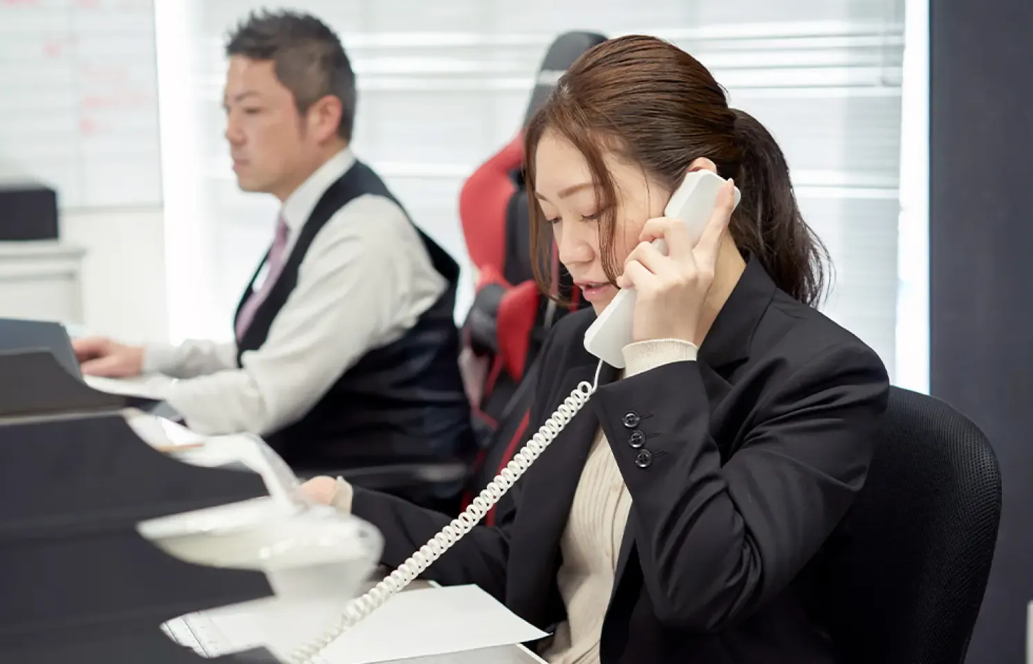 女性が固定電話で話している様子。