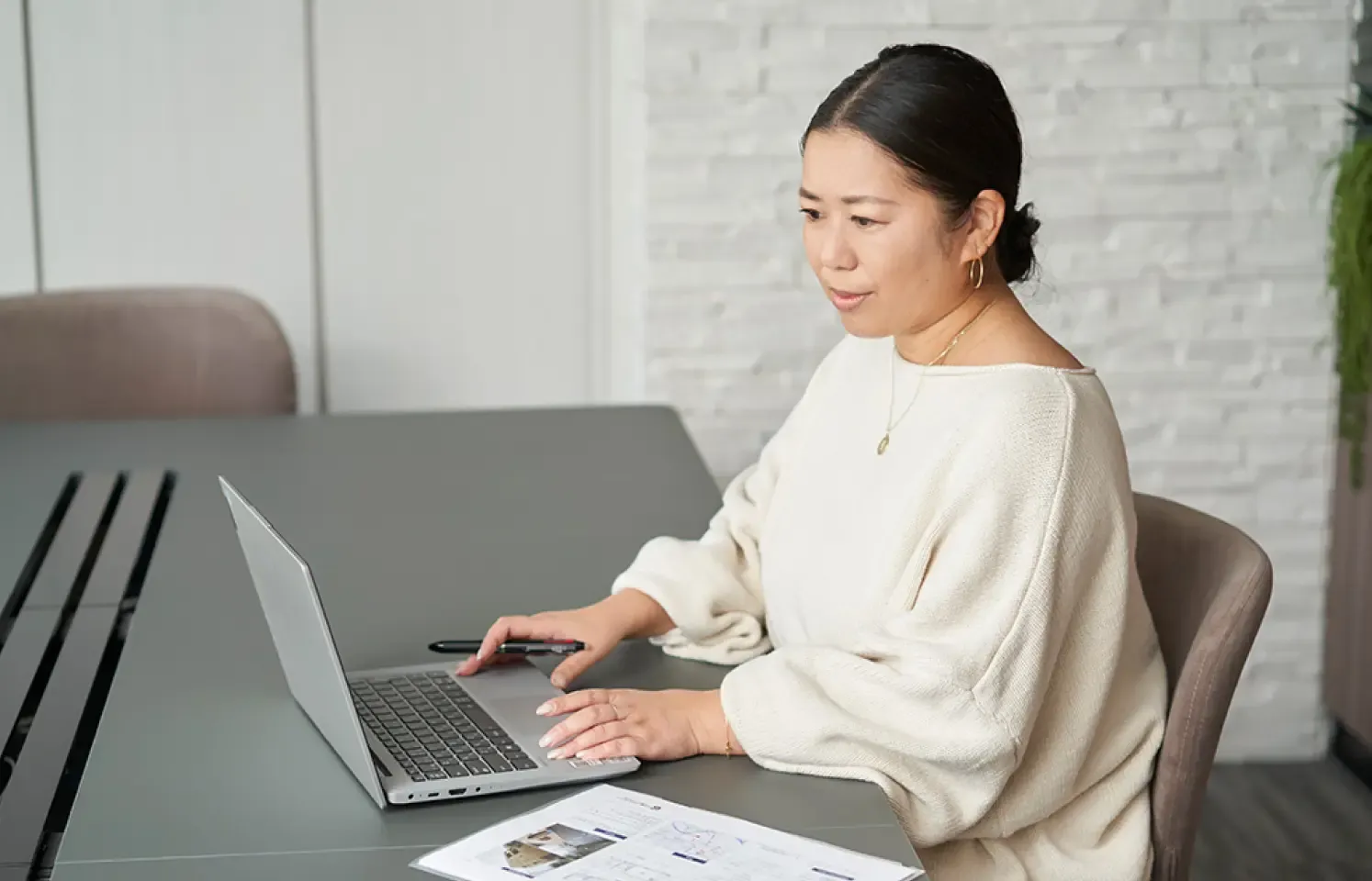 女性がPCを使用して仕事をしている様子。